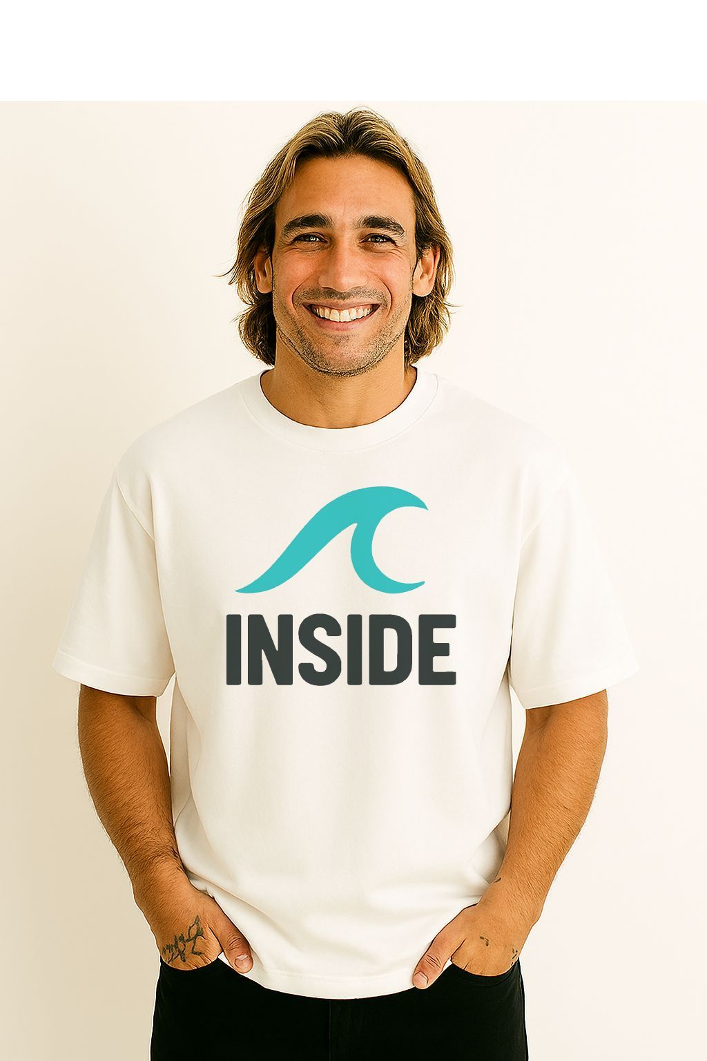 Homem vestindo uma camiseta branca com um logotipo azul-petróleo que diz "DENTRO". Ele está sorrindo, com as mãos nos bolsos.