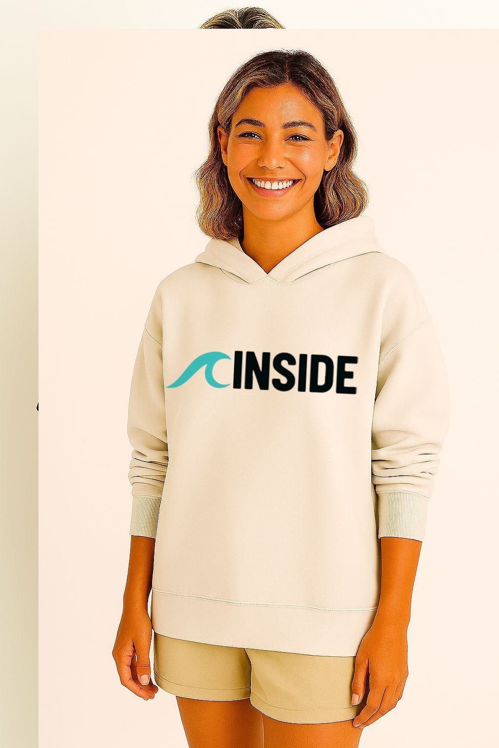 Mulher vestindo um moletom bege com a palavra "INSIDE" e um logotipo de onda azul. Ela está sorrindo.