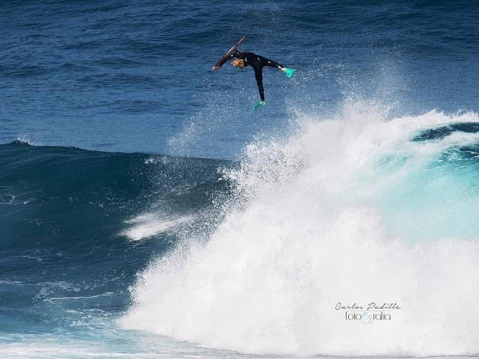 Praticante de bodyboard no ar sobre ondas do oceano, água azul-turquesa e respingos.