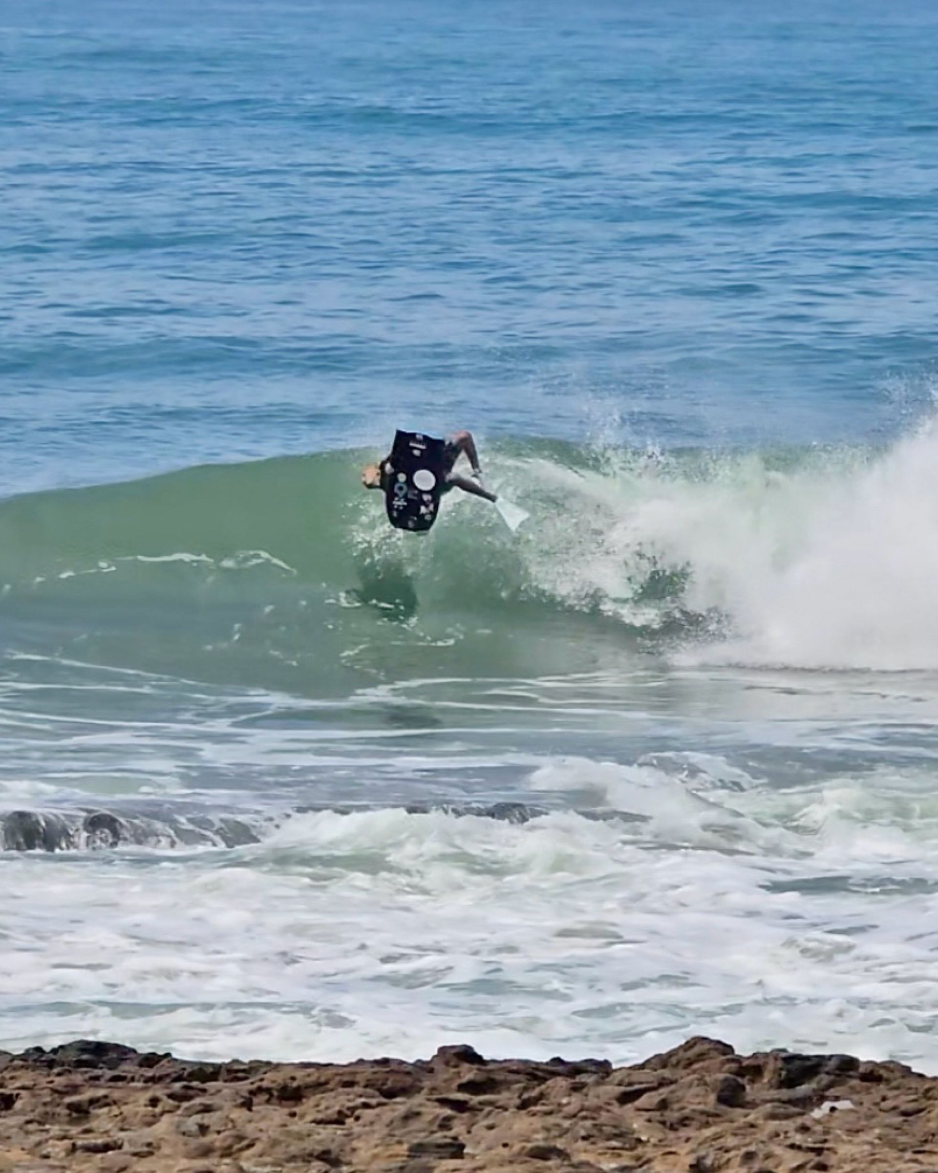 Pessoa praticando bodyboard no oceano, pegando uma onda.