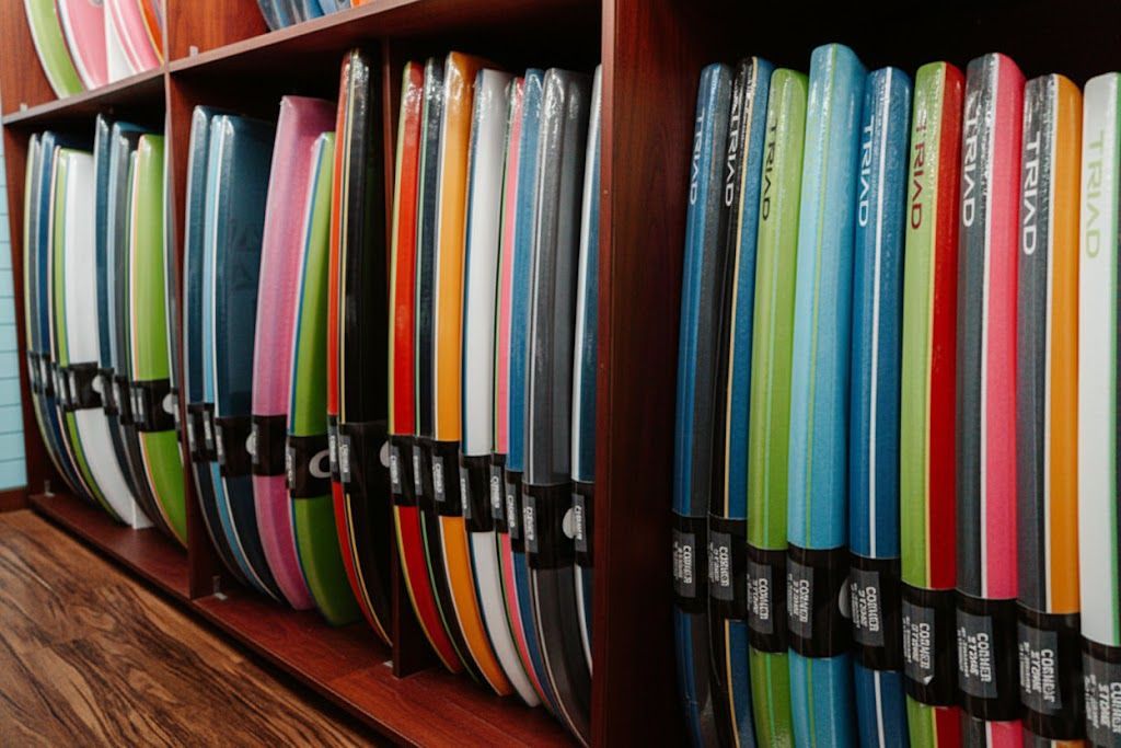 Pranchas de surf de diversas cores, cuidadosamente guardadas em prateleiras de madeira.