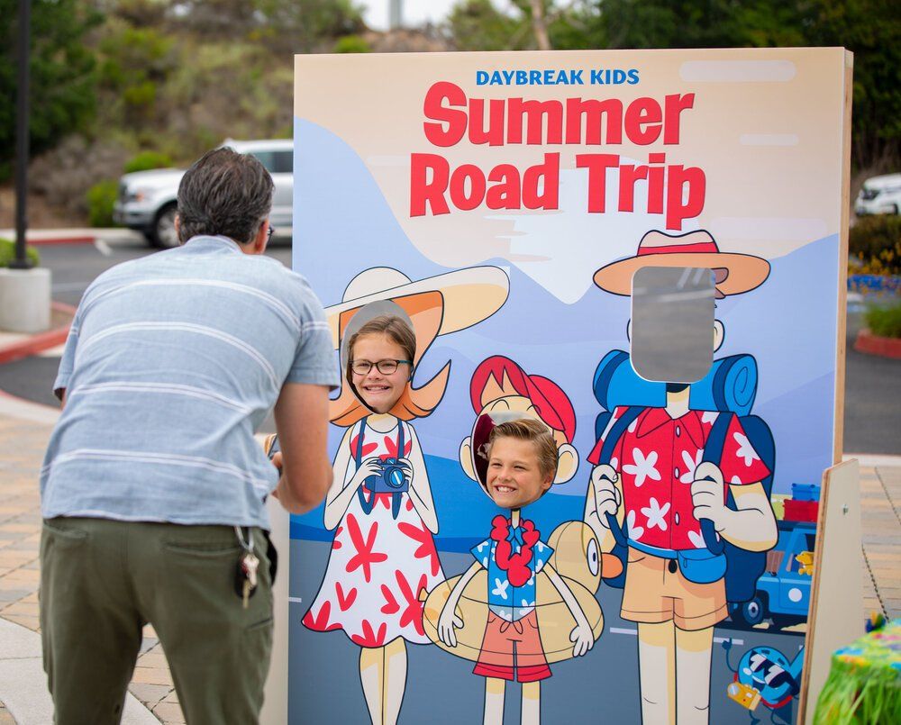 A man is standing in front of a summer road trip photo booth