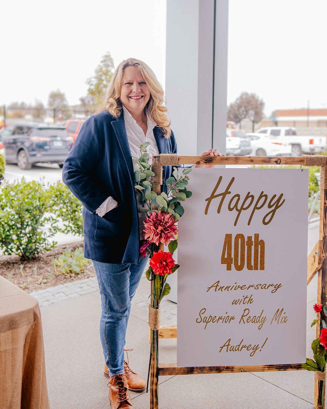 A woman is standing next to a sign that says `` happy 40th anniversary ''.