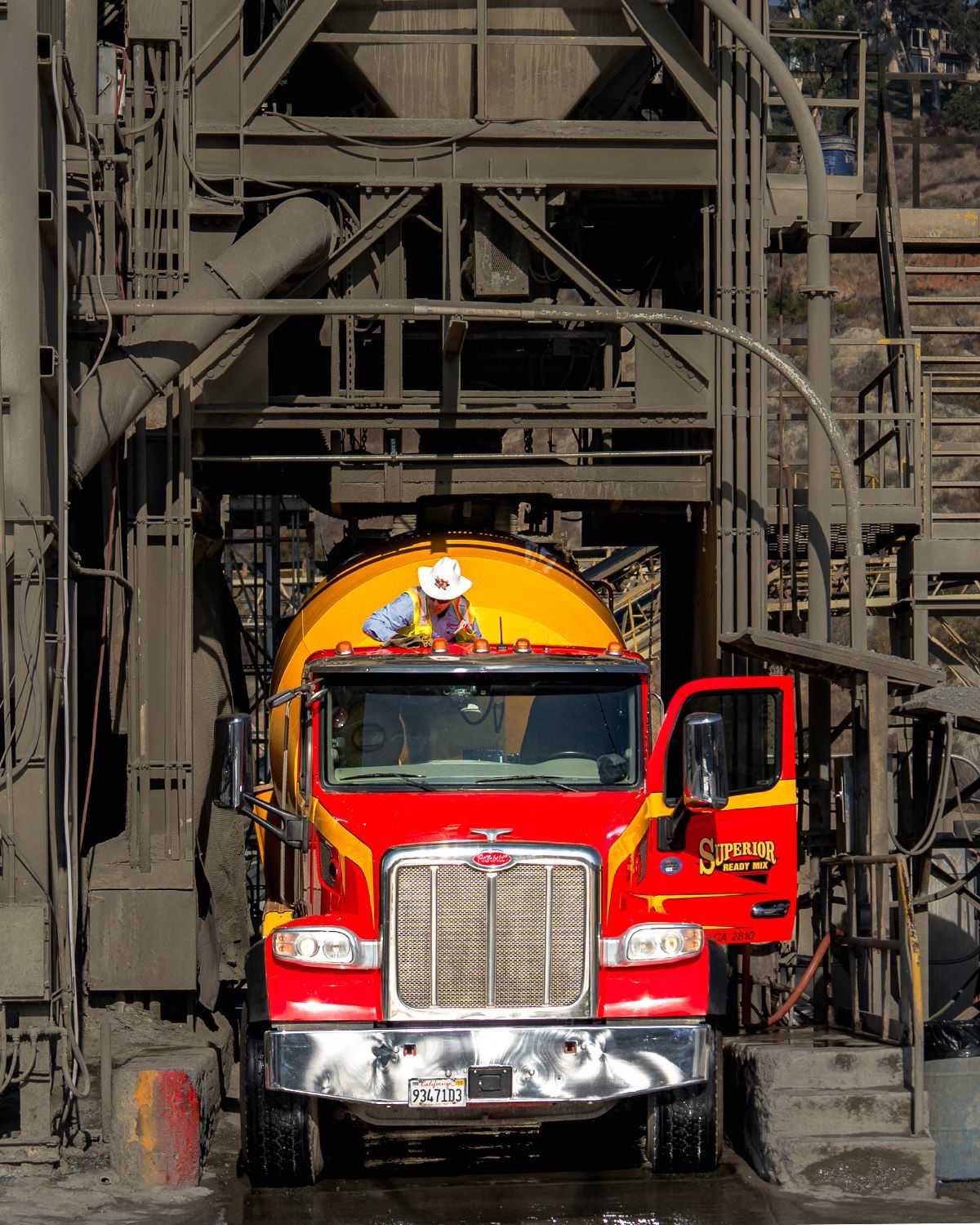 A red and yellow semi truck with a man sitting on top of it