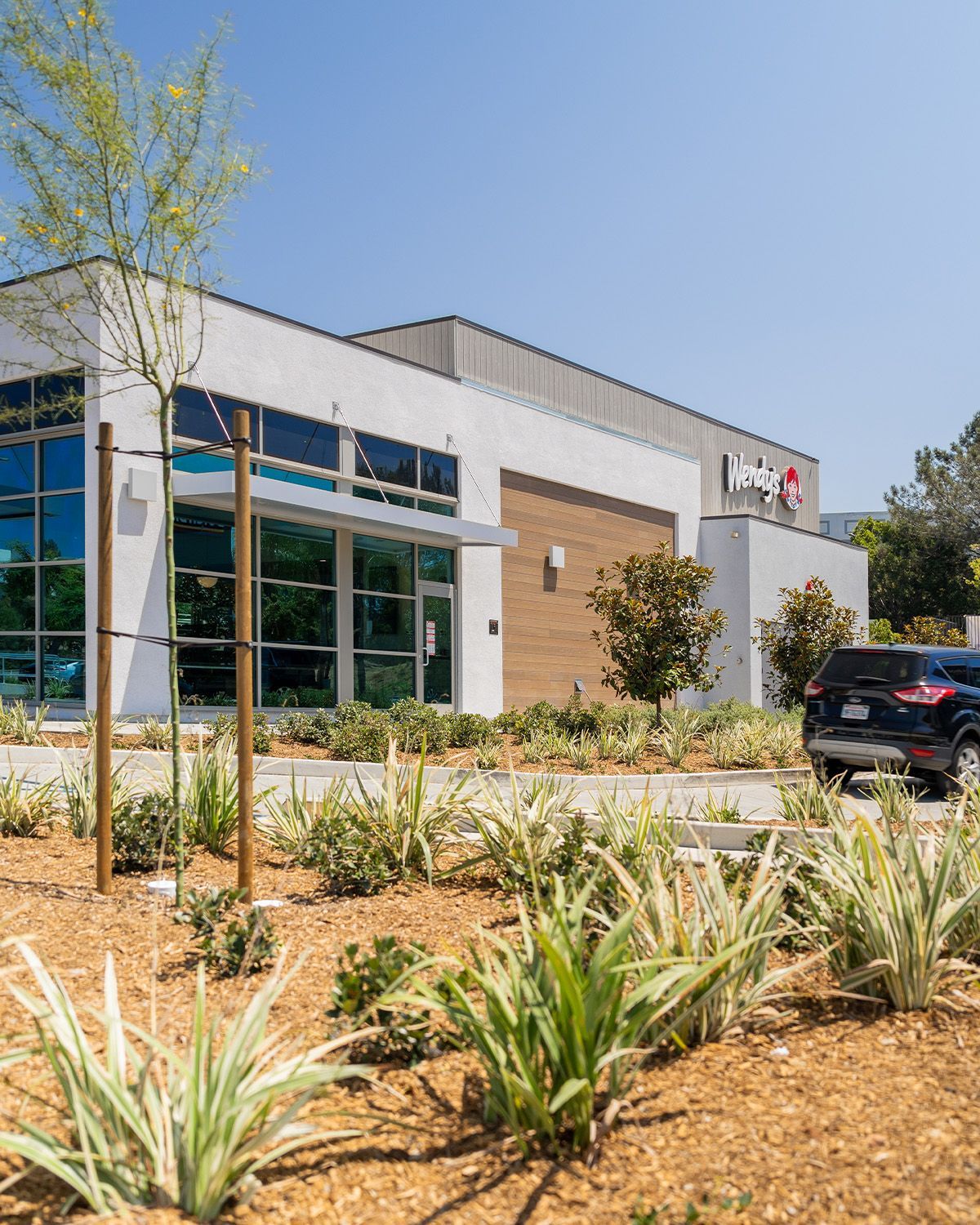 A large white building with a lot of windows and a car parked in front of it.