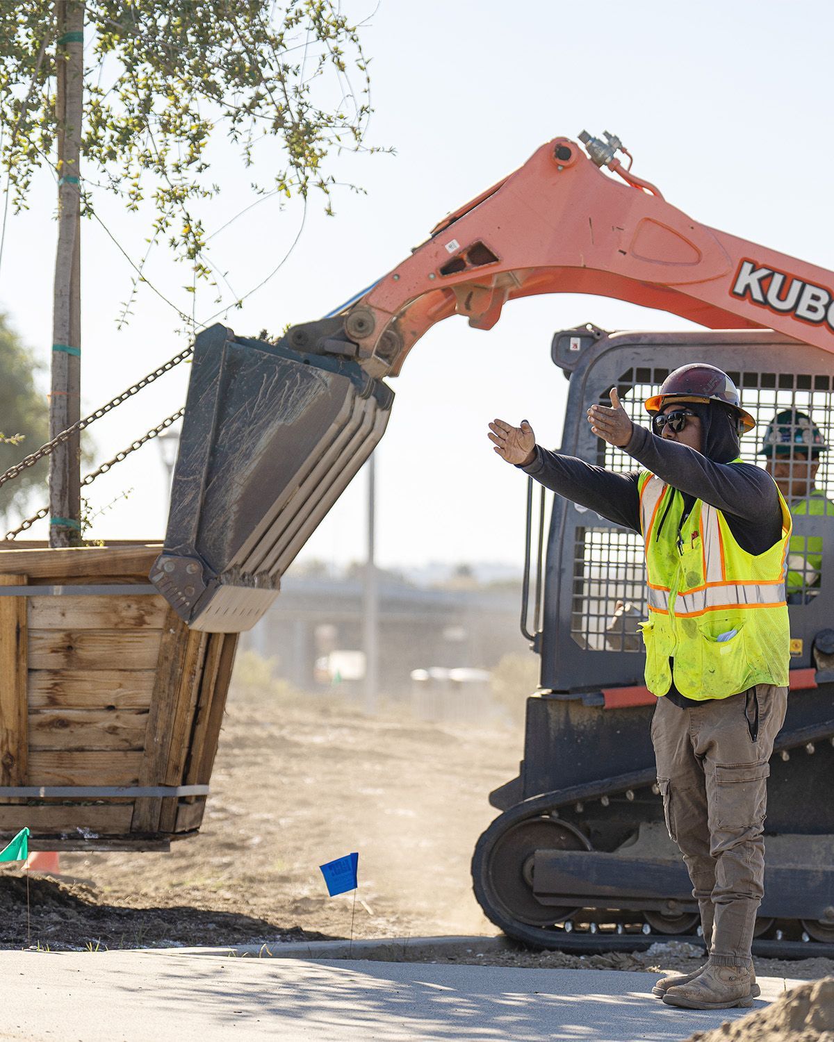 A man in a yellow vest is standing next to a bulldozer.