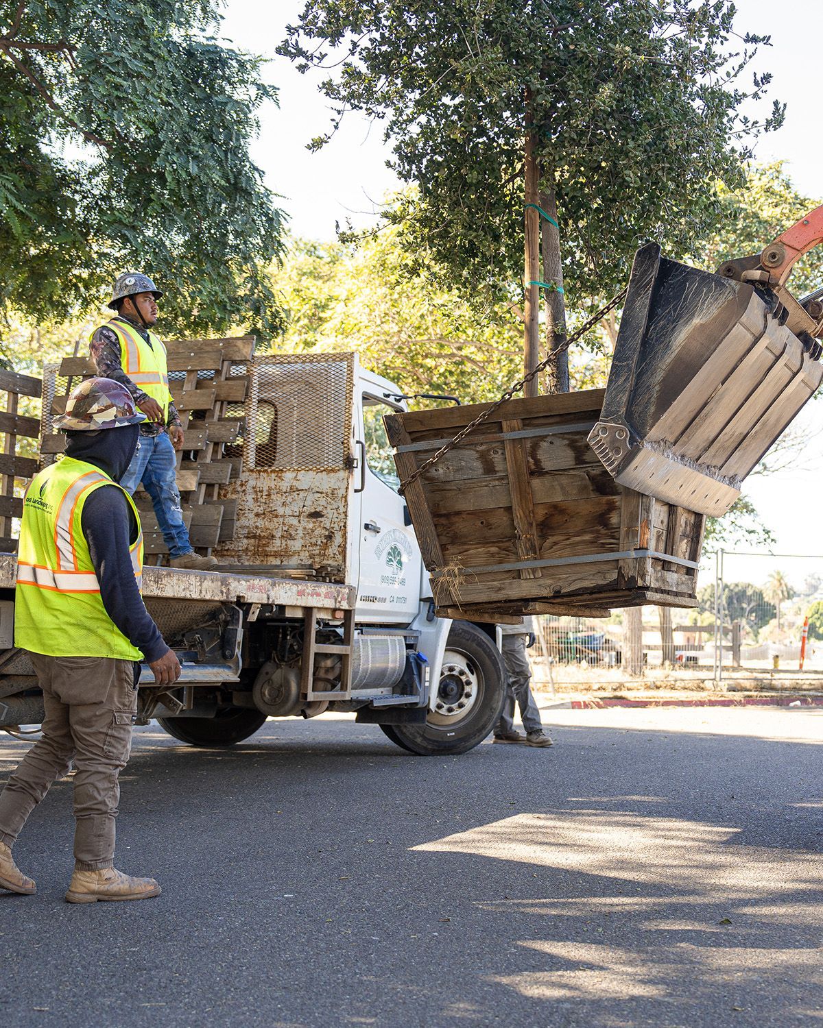 A man in a yellow vest is standing next to a dump truck.