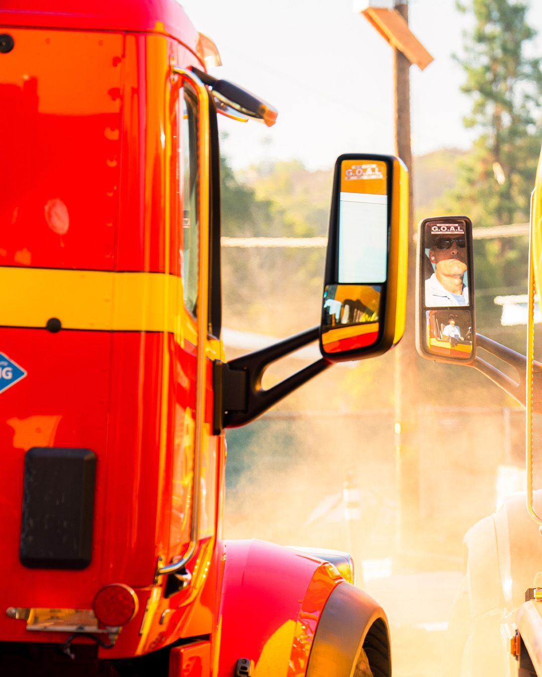A red and yellow semi truck is parked on the side of the road.