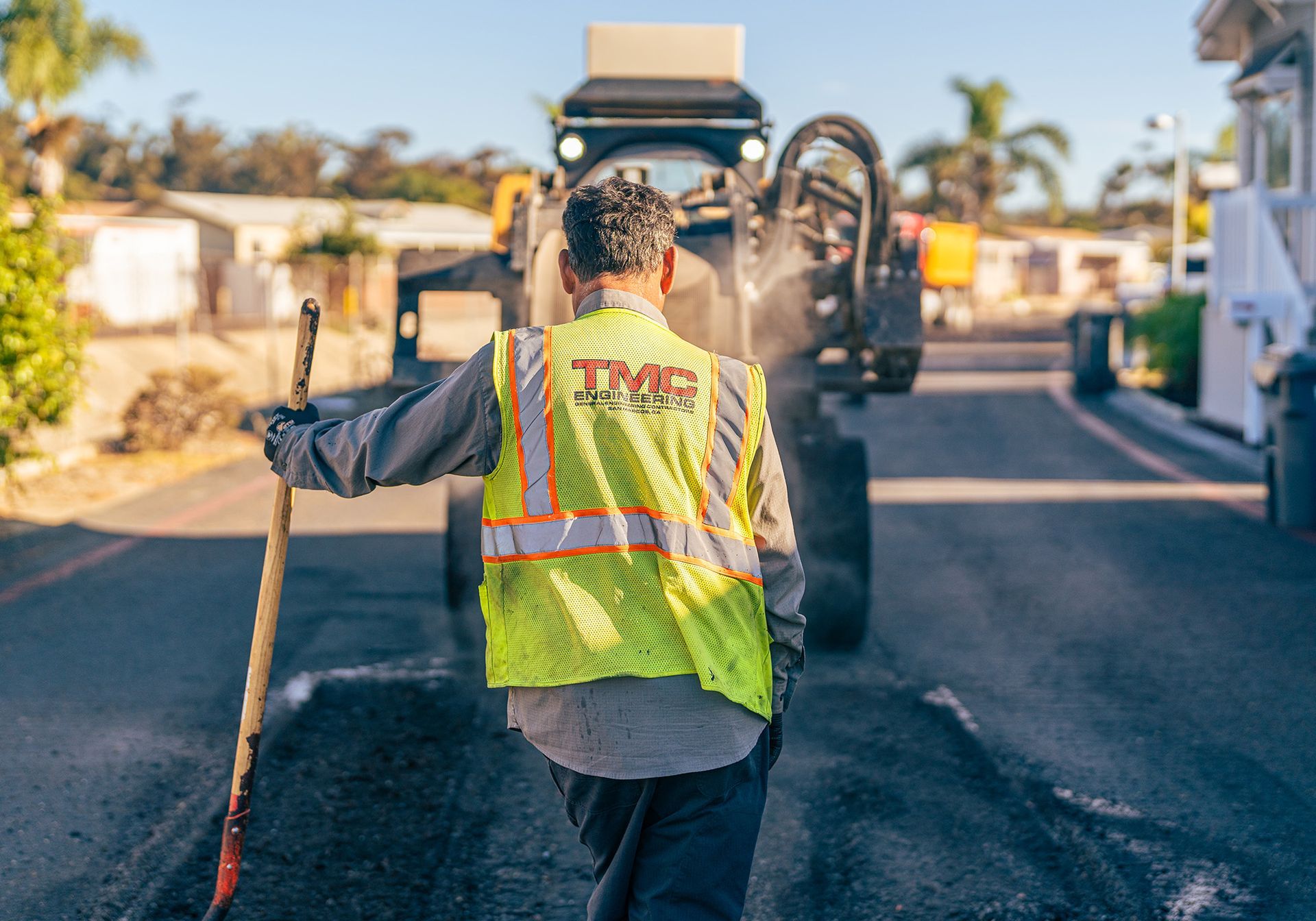 A man in a yellow vest is walking down a street.