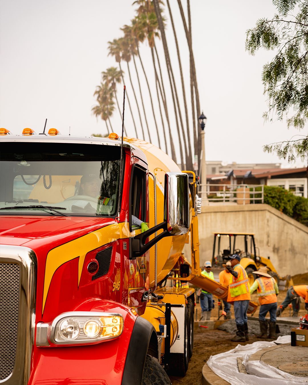 A red and yellow truck is parked in front of a construction site.