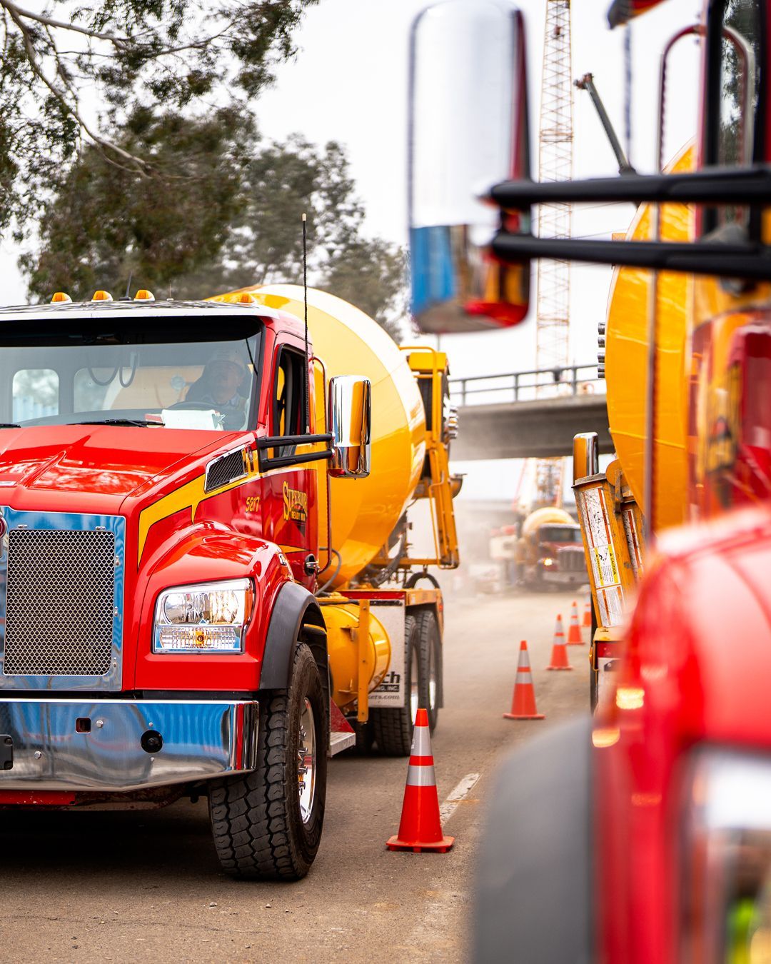 A red and yellow truck is parked on the side of the road next to a yellow truck.