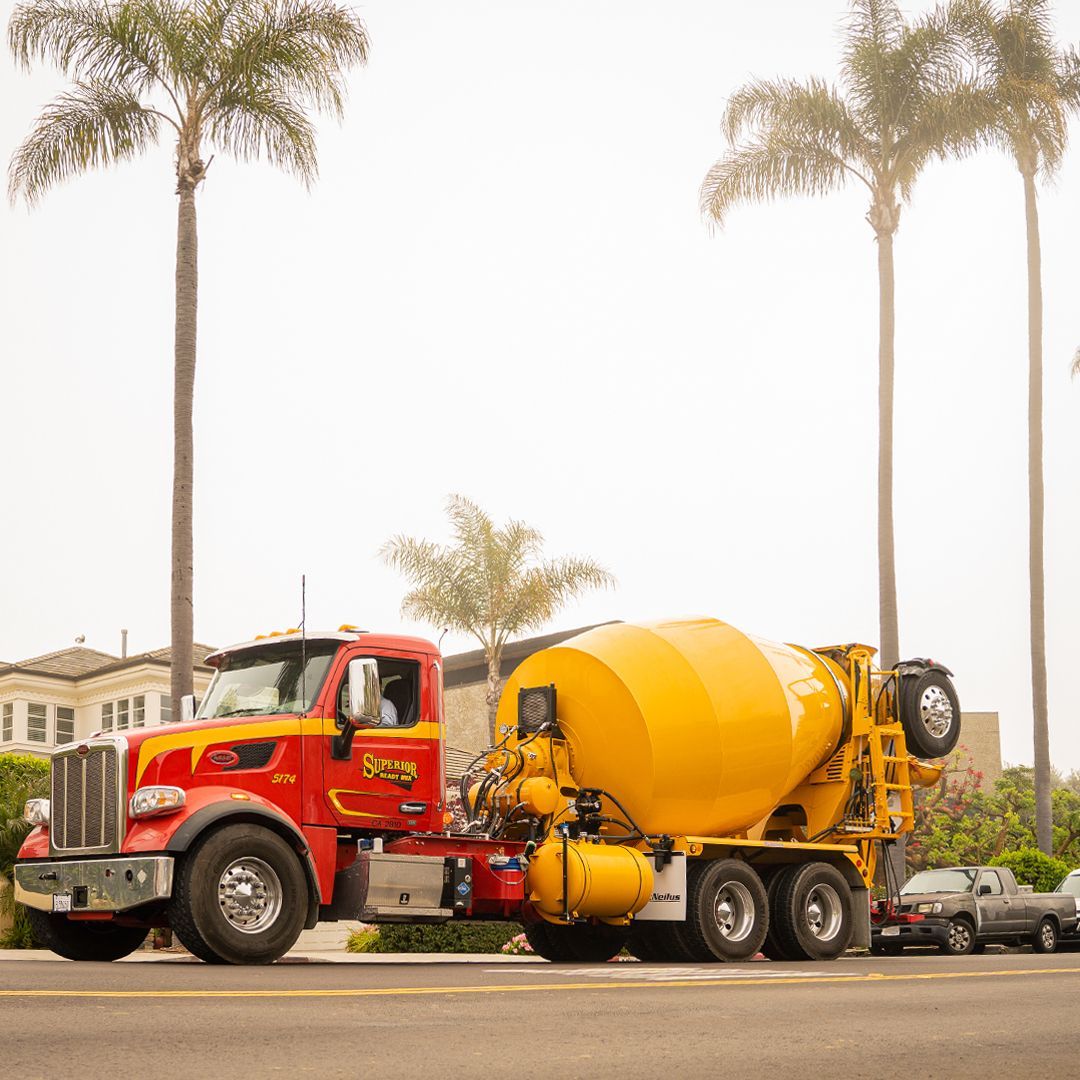 A red and yellow concrete mixer truck is parked on the side of the road.
