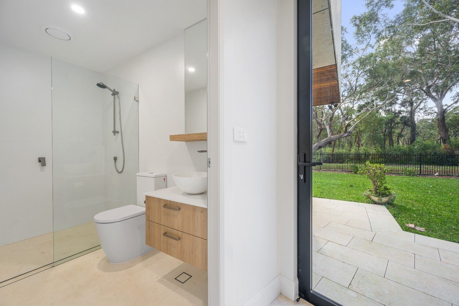 Bathroom with Shower, Toilet, Vanity, and Open Door to A Backyard with Trees and Grass — Concept Kitchens In Port Macquarie, NSW
