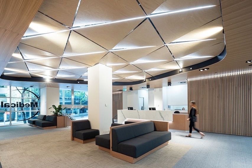 A Woman Is Walking Through A Lobby With A Couch — Concept Kitchens In Port Macquarie, NSW
