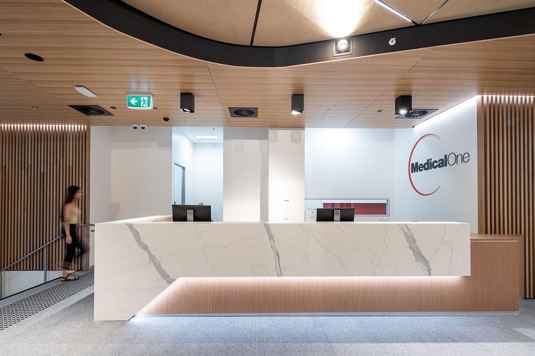 A Woman Is Walking Past A Reception White Desk In A Building — Concept Kitchens In Port Macquarie, NSW