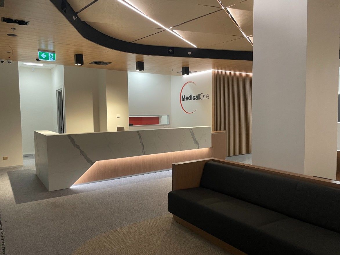 A Waiting Room With A Dark Green Couch And A Reception Desk — Concept Kitchens In Port Macquarie, NSW