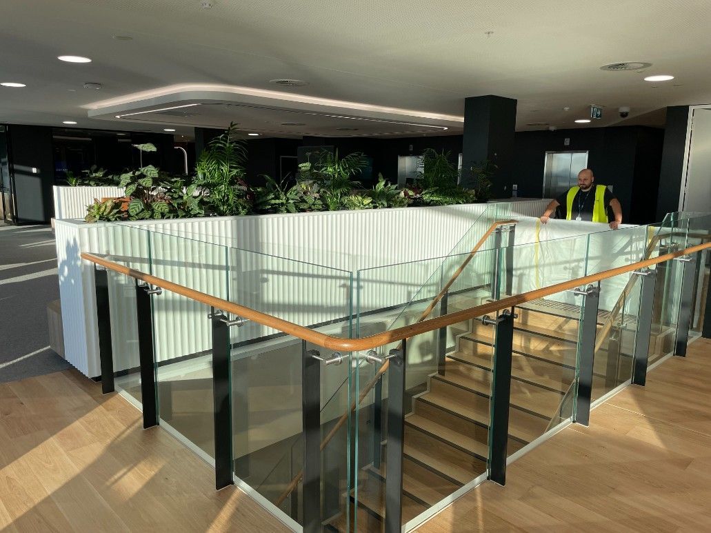 A Man In A Yellow Vest Is Standing On The Stairs Of A Building — Concept Kitchens In Port Macquarie, NSW