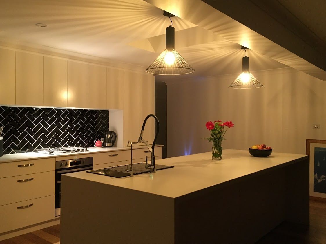 A kitchen with a large island and a vase of flowers on the counter.— Concept Kitchens In Port Macquarie, NSW