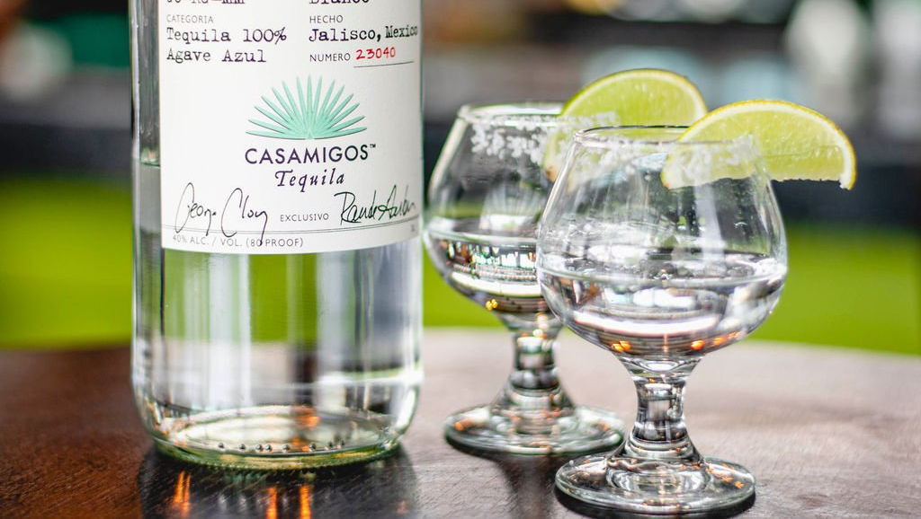 A bottle of tequila and two glasses of tequila on a table.