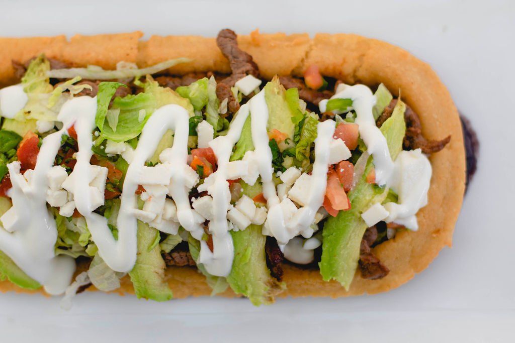 A sandwich with lettuce , tomatoes , and sour cream on a white plate.