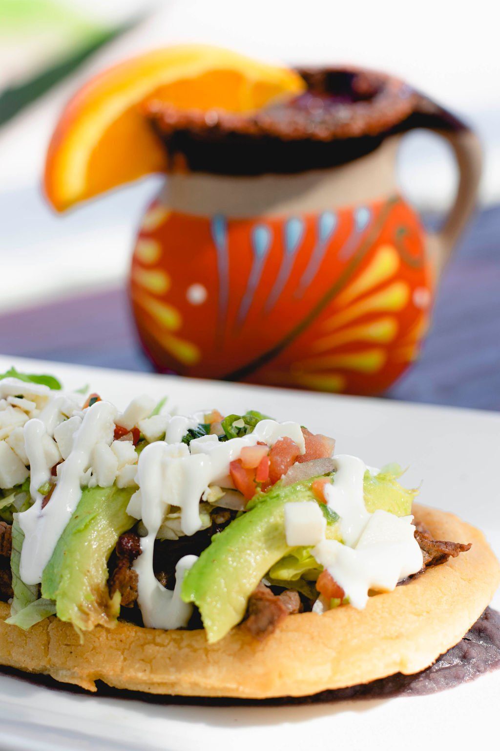 A close up of a plate of food with a pitcher in the background