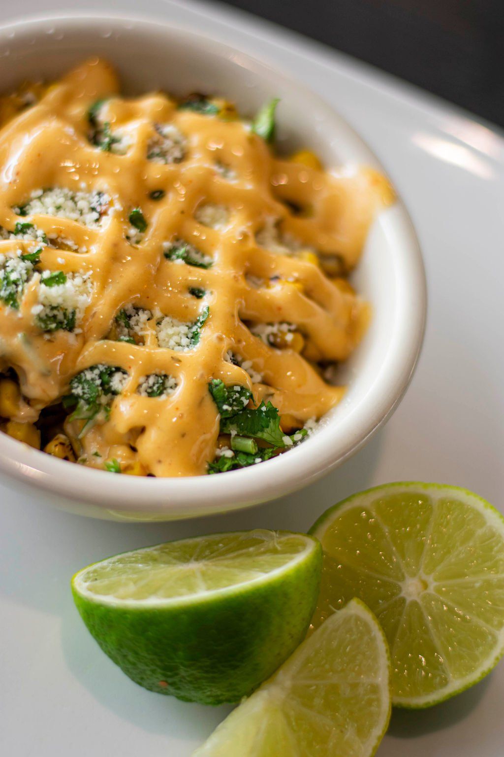A bowl of food with cheese and limes on a table.