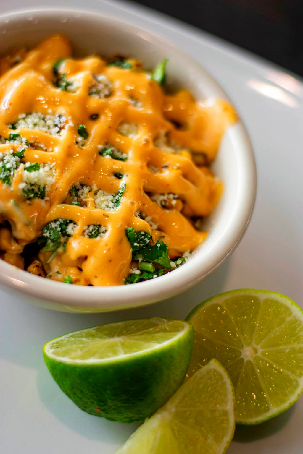 A bowl of food with cheese and limes on a table.