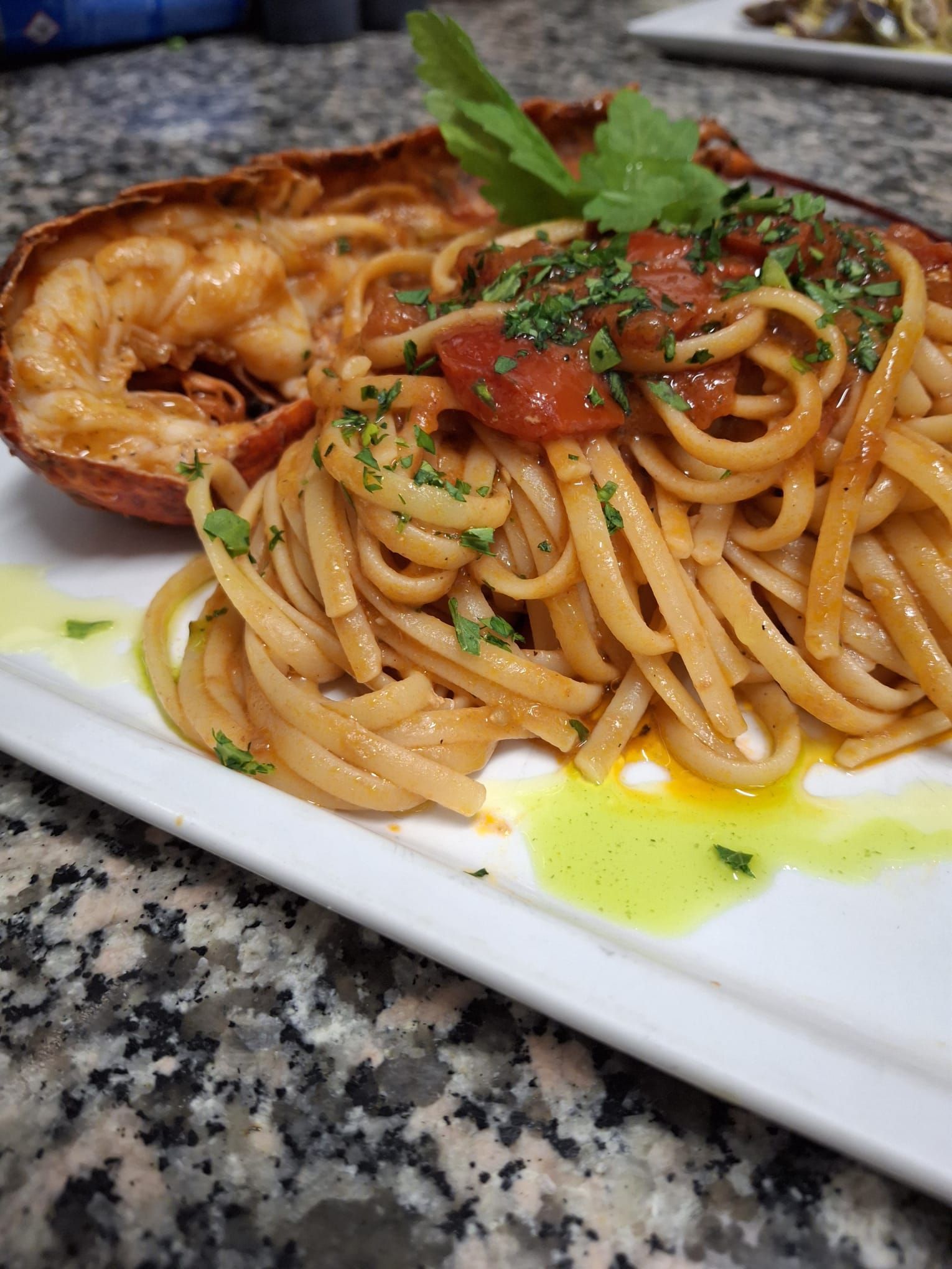 Pasta al sugo di pomodoro, guarnita con prezzemolo, servita con aragosta.