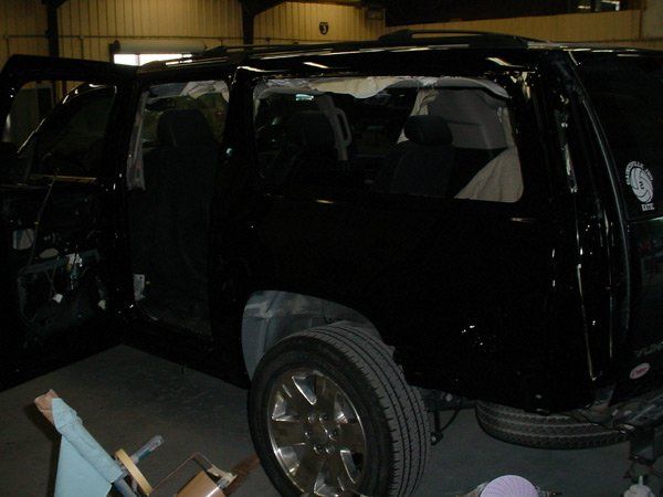 Black SUV with missing windows and open doors in a garage.