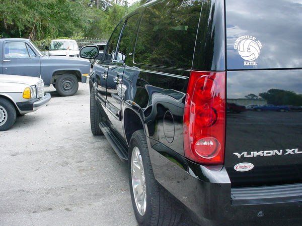 Black GMC Yukon XL SUV, rear view, parked in lot. Other vehicles visible.