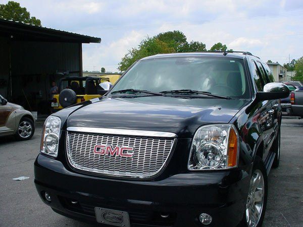 Black GMC Yukon SUV with chrome grill parked outdoors.