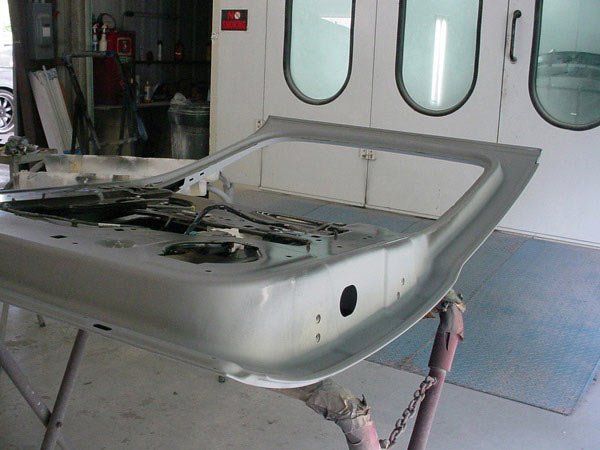 Car door frame in a body shop, on a stand, being prepped for painting.