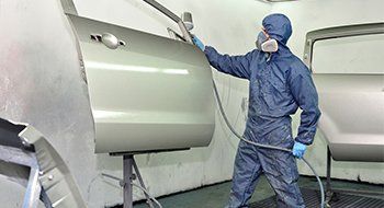 Worker painting car door.