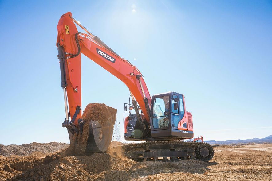 Orange excavator digging in a dirt field under a bright blue sky.