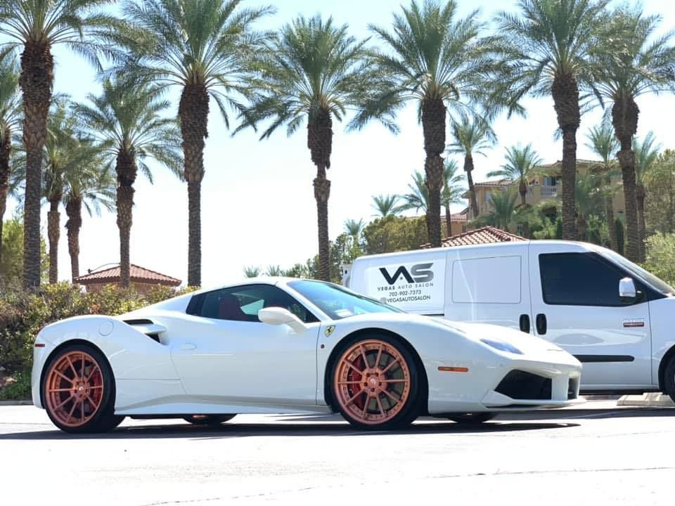 A white ferrari is parked next to a white van.