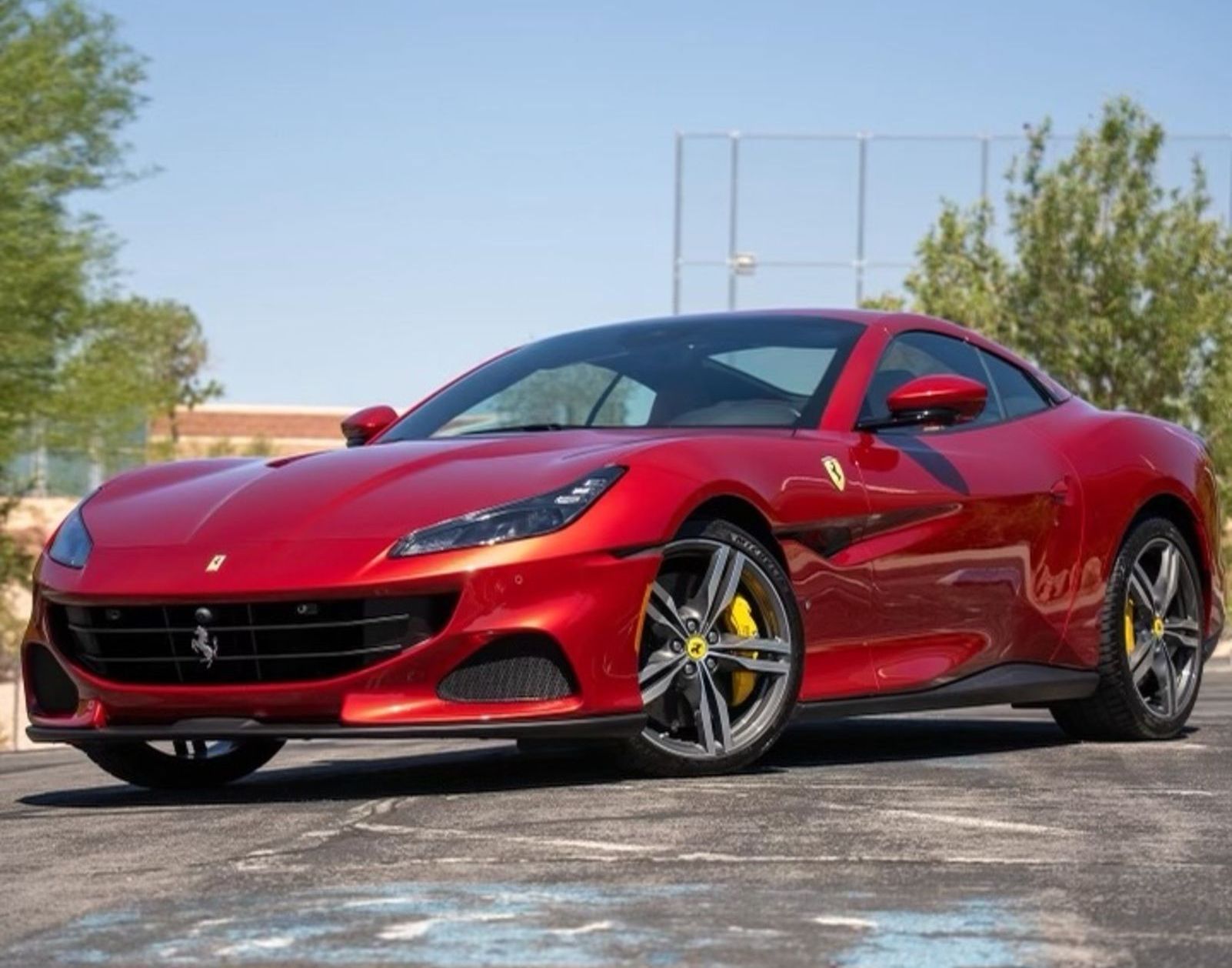 A red ferrari is parked in a parking lot.