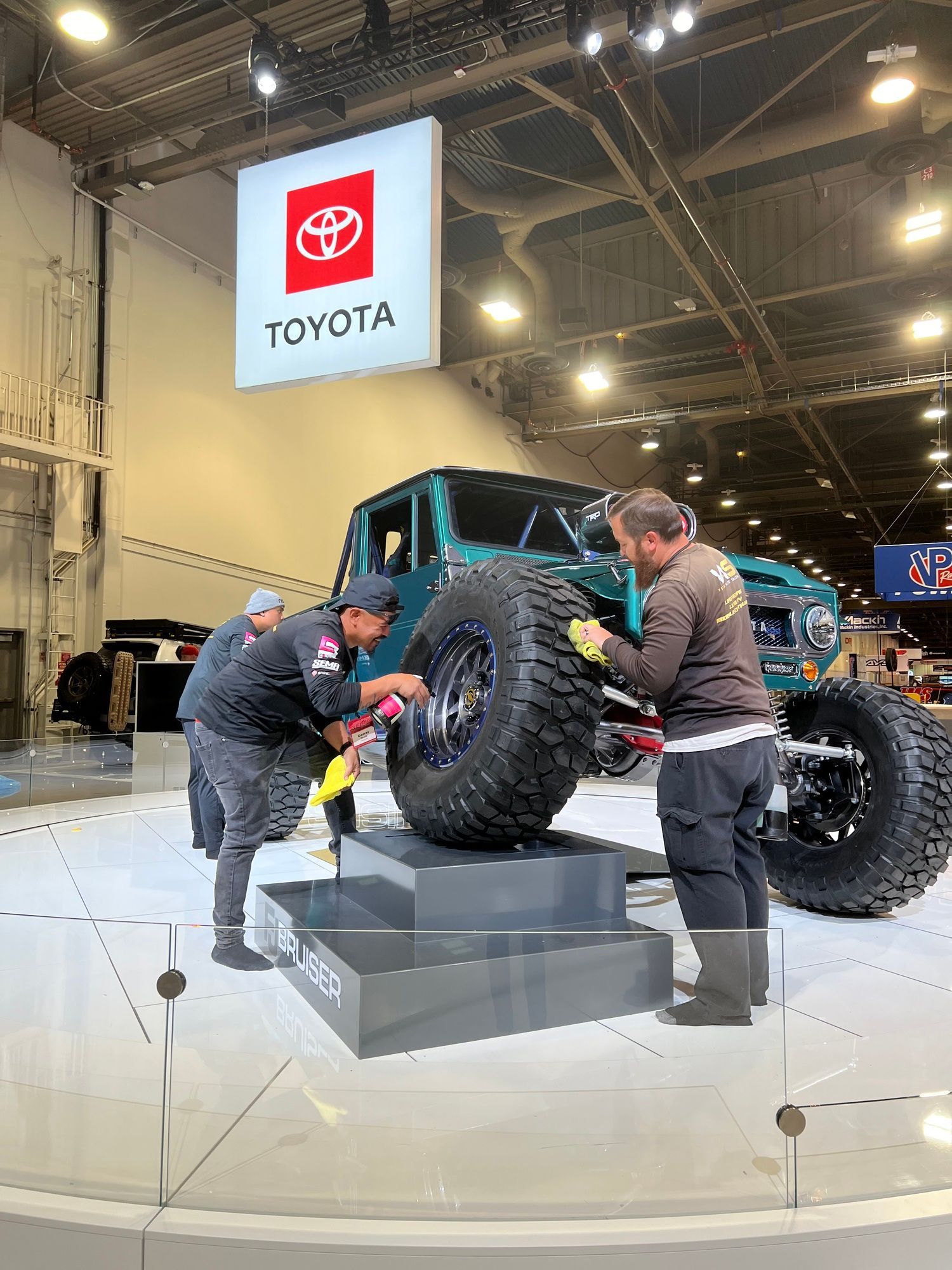A group of men are working on a toyota truck at a car show.