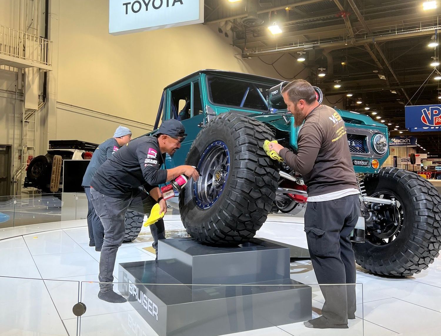 A group of men are working on a toyota truck at a car show.