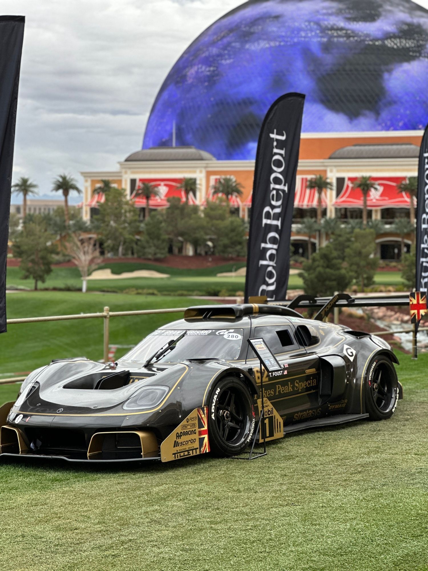 A race car is parked on the grass in front of a building.