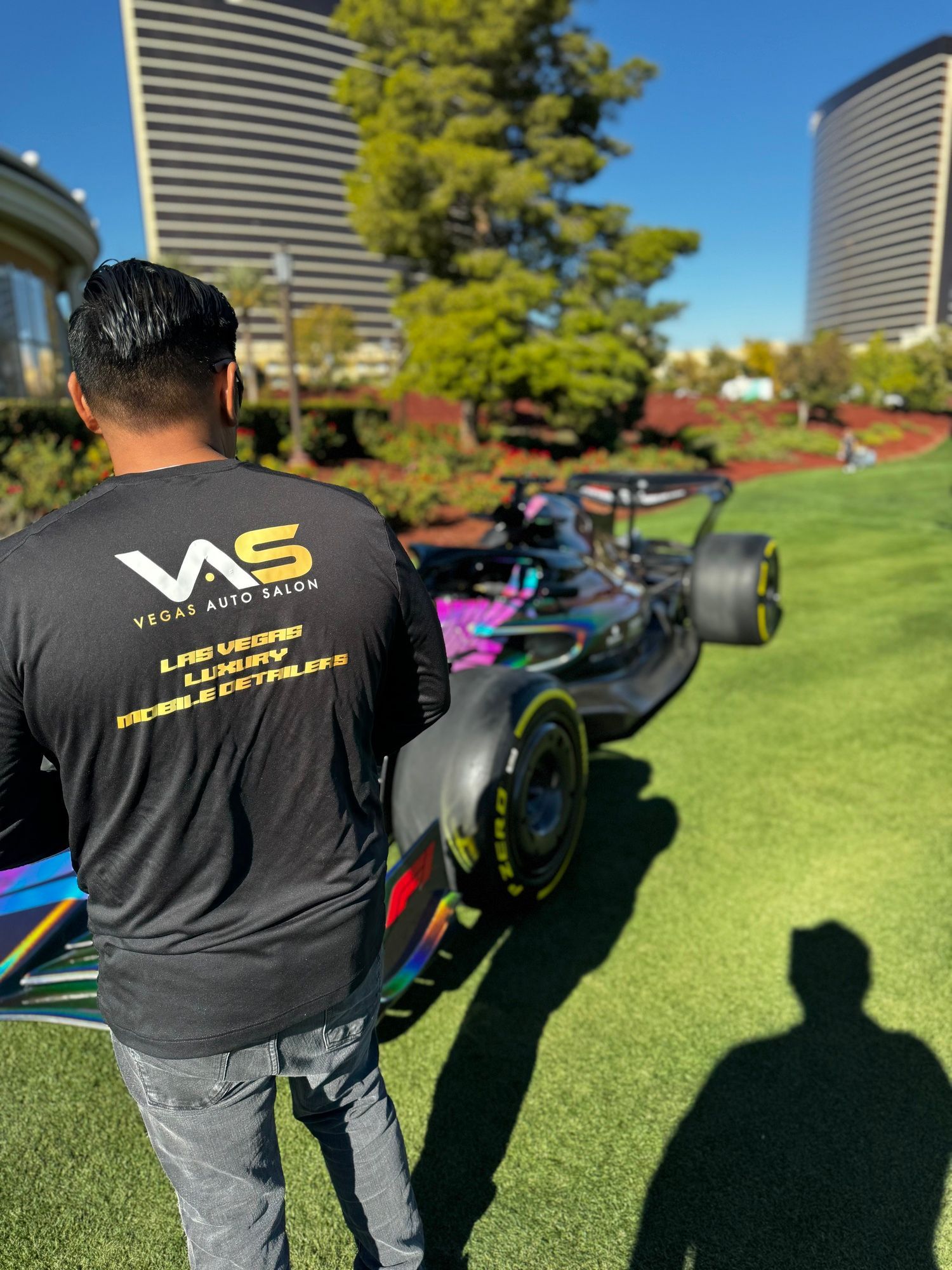 A man wearing a ws shirt is standing in front of a race car
