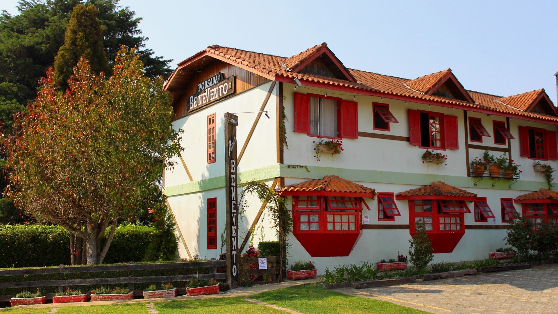 Uma grande casa branca com persianas vermelhas e um telhado- Pousada Benevento