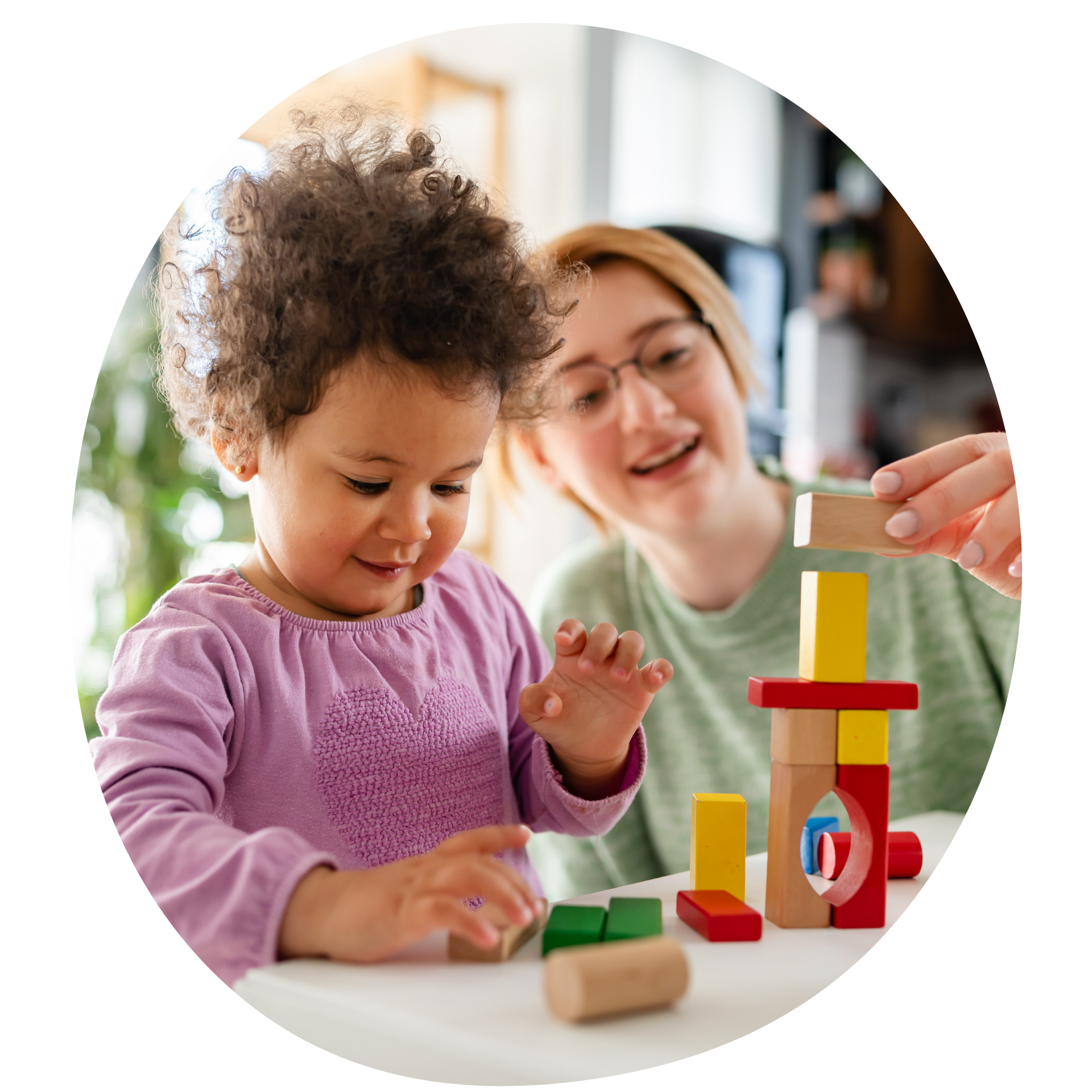 Child and adult playing with colorful building blocks on a white table.