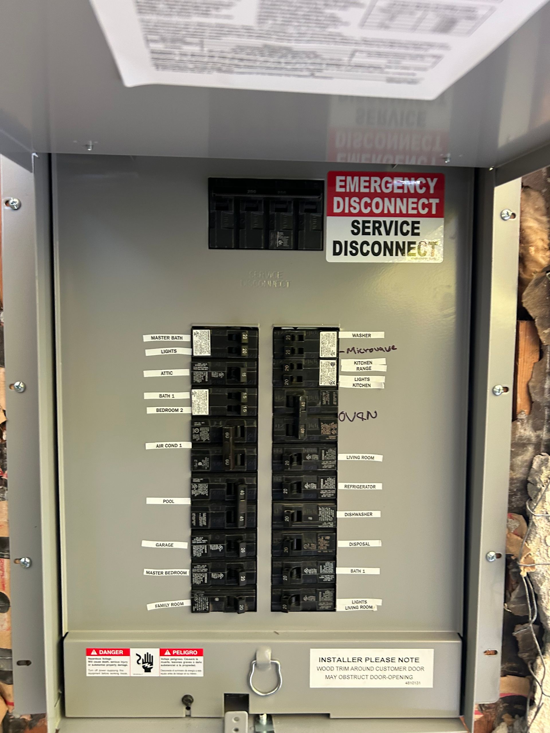 Electrical service panel with breakers and a warning sign reading “EMERGENCY DISCONNECT / DISCONNECT”