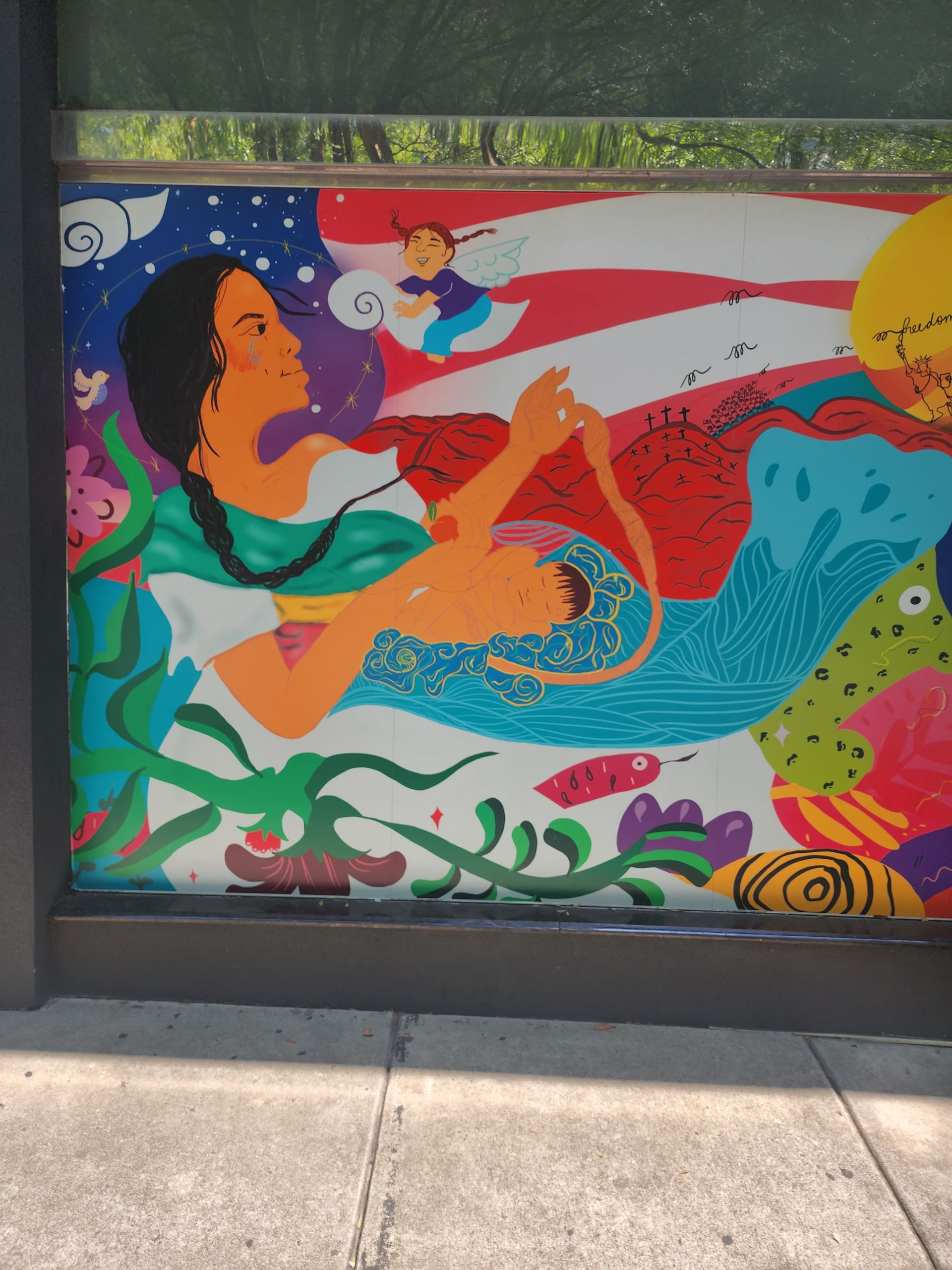 Colorful mural of a person holding a baby, in front of an American flag design.