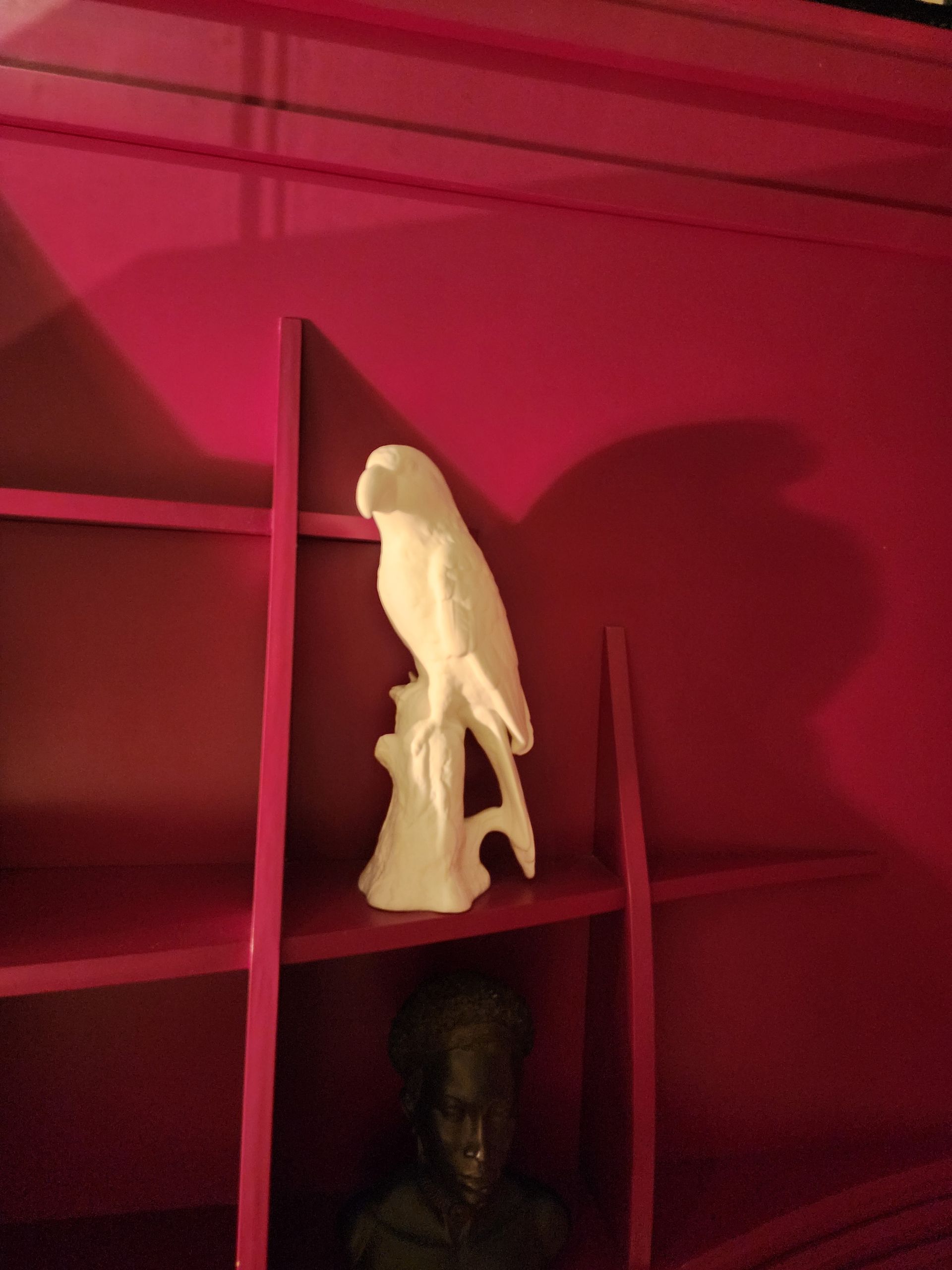 White parrot figurine on red shelf.