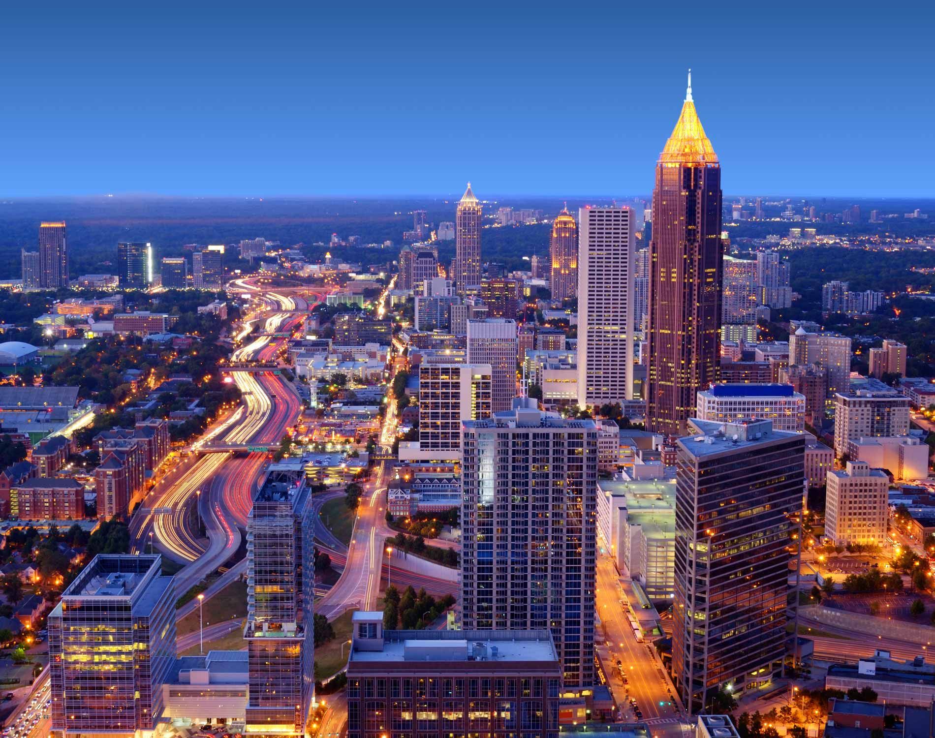 Atlanta skyline at dusk with lit buildings and busy highway.