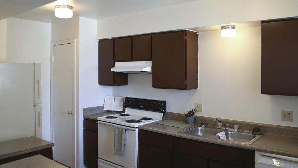 Kitchen with brown cabinets, white appliances, and a gray countertop.