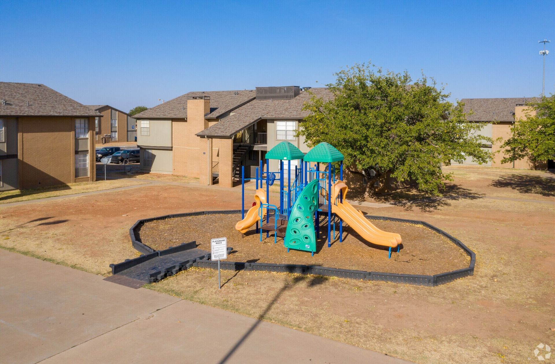 Playground in front of apartment buildings on a sunny day.