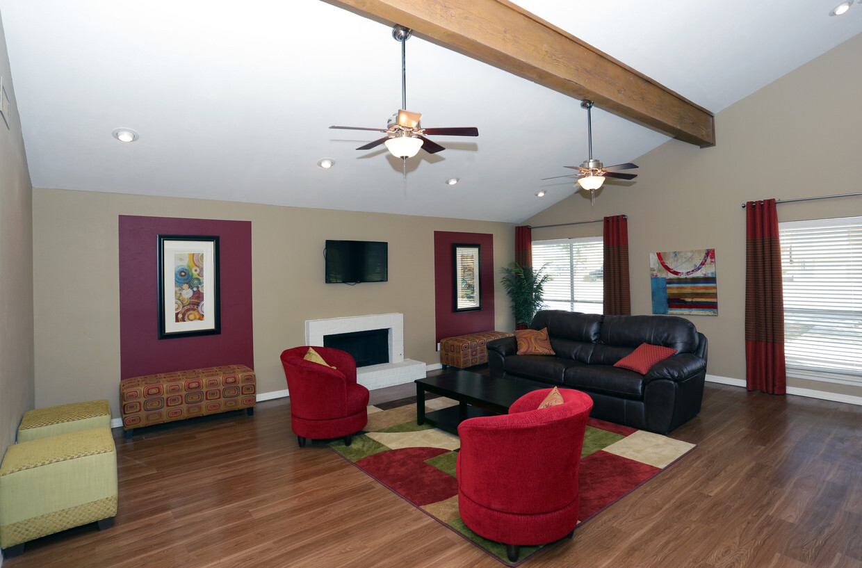 Living room with brown leather sofa, red chairs, fireplace, and hardwood floors.