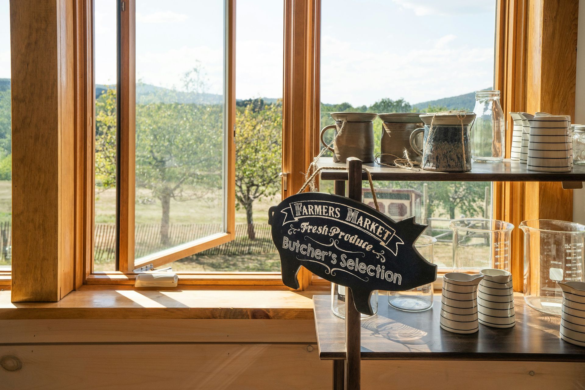 A sign on a table in front of a window with a view of a field.